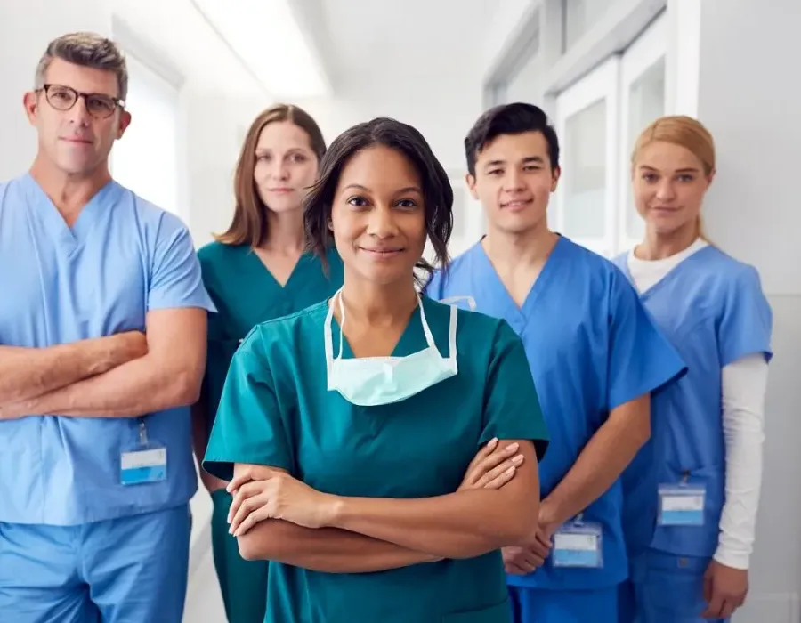 Team of nurses and healthcare staff smiling in hospital corridor